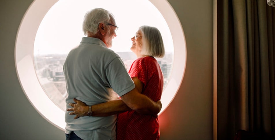Older couple embracing in front of round window